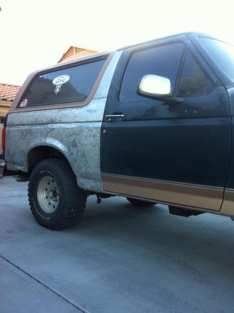 1994 Ford Bronco - This Ford Bronco shows significant body damage and mismatched paintwork on its exterior.