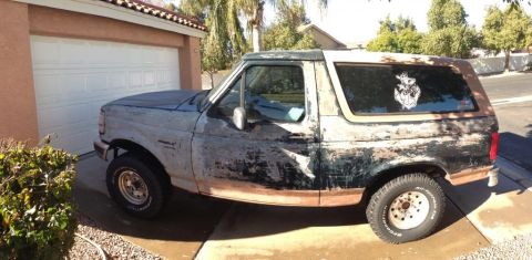 1994 Ford Bronco - This older model Ford Bronco is parked in front of a garage with a sticker on the rear window.