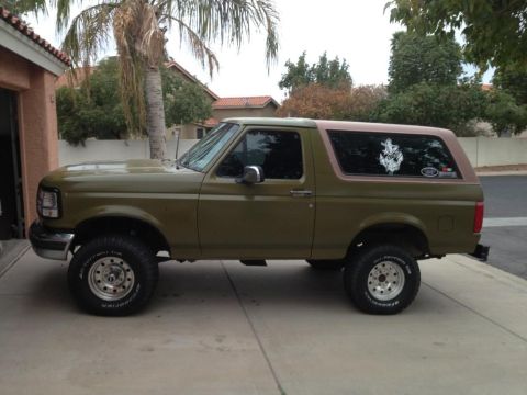 1994 Ford Bronco - Side view of an olive green Ford Bronco, likely from the 1992-1996 generation.