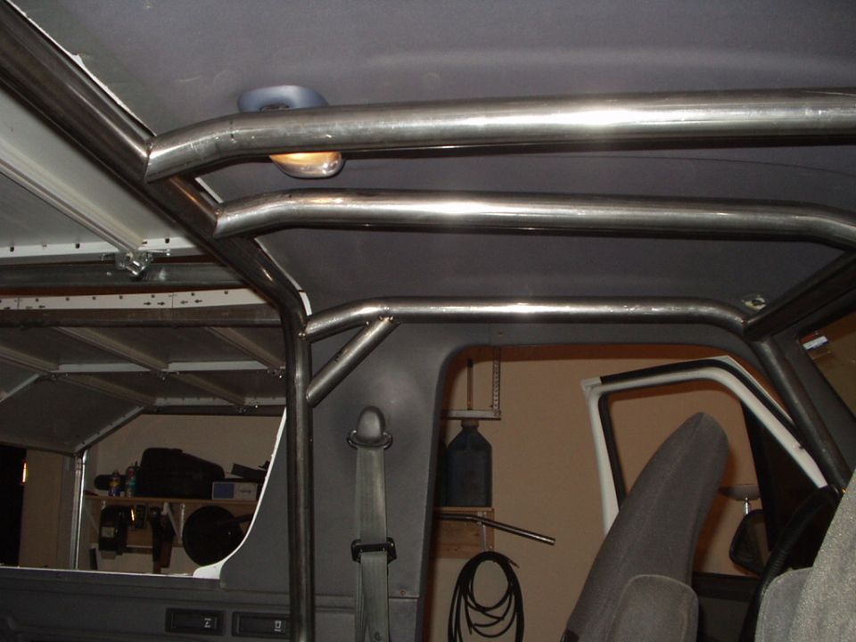 Custom welded roll cage tubing inside gray SUV interior near headliner