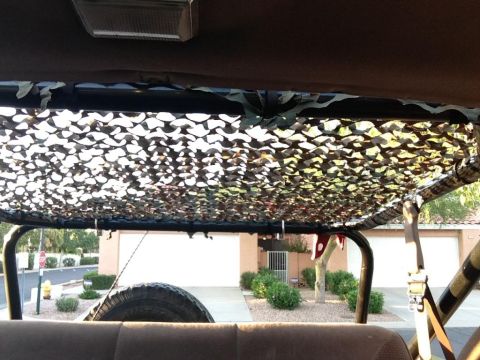 1994 Ford Bronco - Camouflage netting covers the roof rack inside this vehicle, with a spare tire visible.