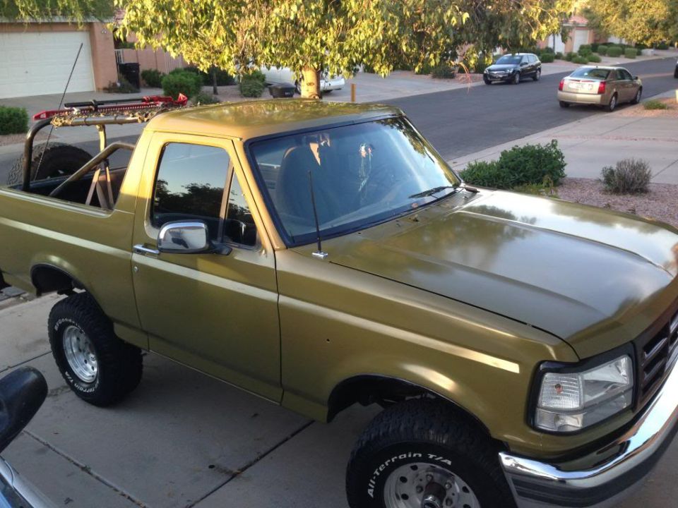Gold 1994 Ford Bronco with roll cage and lifted suspension, 3q-front view