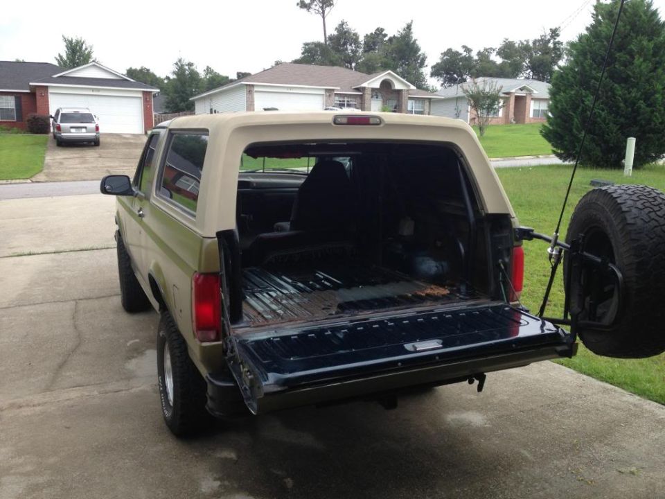 Green and tan 1994 Ford Bronco rear view with tailgate open and spare tire on back