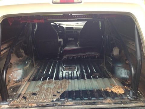 1994 Ford Bronco - Interior view of a 1994 Ford Bronco, modified with a roll cage and showing a dirty cargo area.