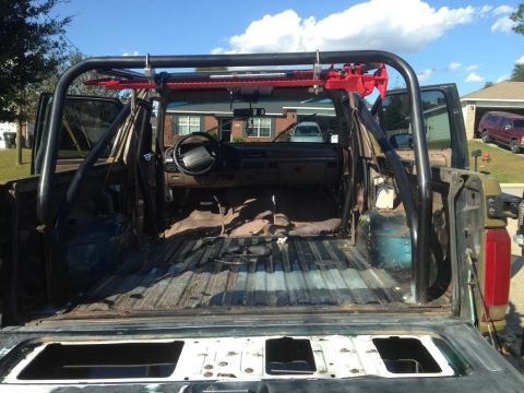1994 Ford Bronco - The interior of an SUV is shown with a roll cage and exposed cargo area, ready for modification.