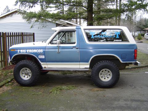 1989 Ford Bronco - Side view of a lifted 1989 Ford Bronco with custom graphics and off-road tires.