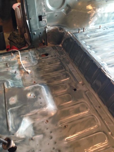 1994 Ford Bronco - The interior floor of a vehicle is shown stripped down, revealing metal and repair work.