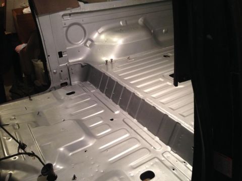 1994 Ford Bronco - The bare interior of a silver vehicle, revealing the floor and cargo space, possibly undergoing restoration.