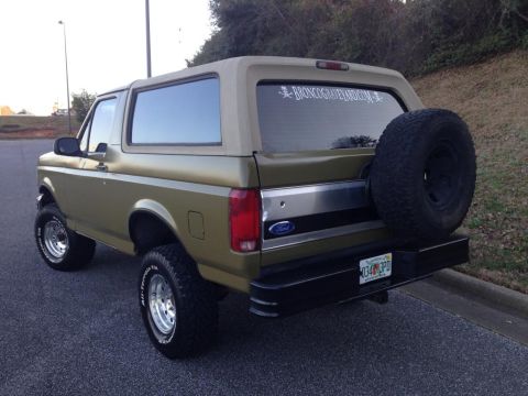1994 Ford Bronco - Rear view of a 1994 Ford Bronco, showing the spare tire and a decal on the rear window.