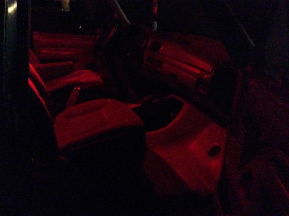 Car interior with red ambient lighting, showing seats and dashboard
