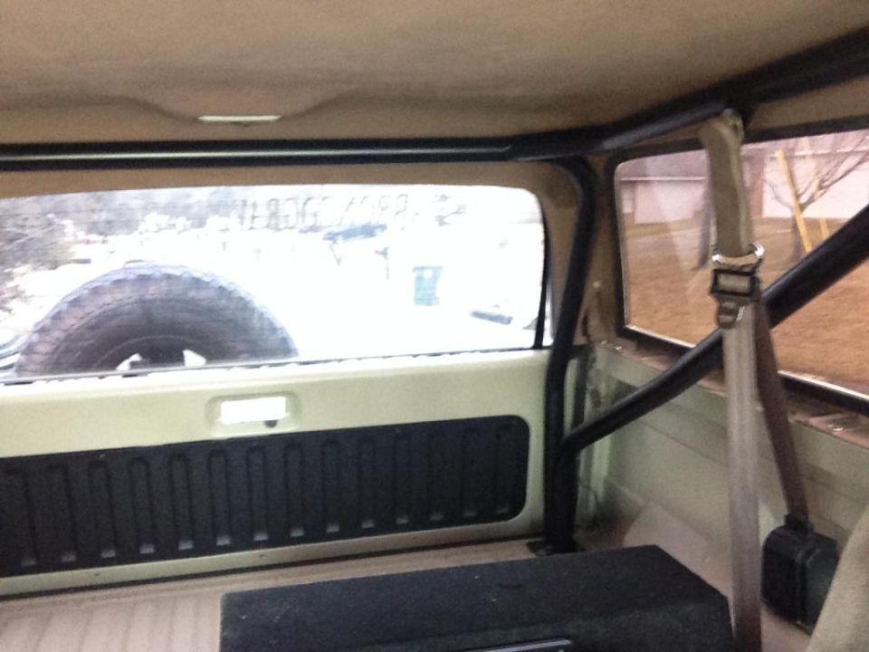 Interior view of a 1994 Ford Bronco showing a roll cage and spare tire