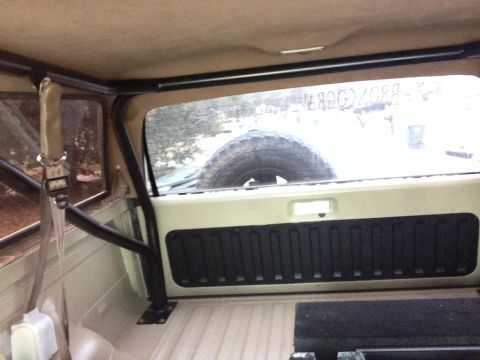 1994 Ford Bronco - Interior shot showing a roll cage and spare tire. Text on rear window is illegible.