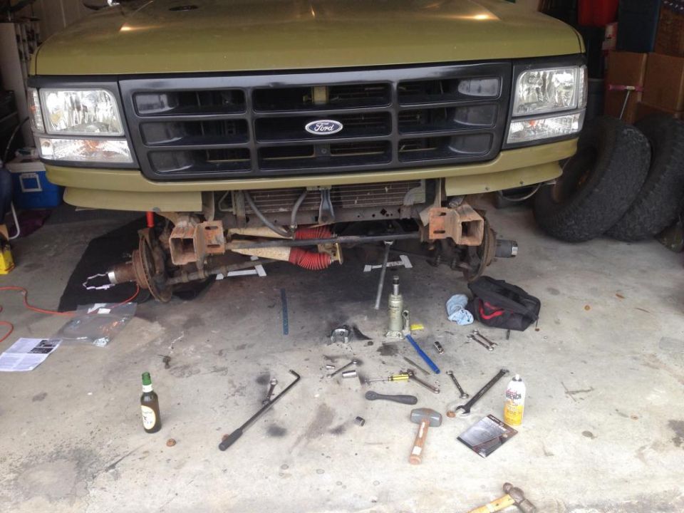 Olive green 1992 Ford Bronco front end with grille removed, showing suspension work