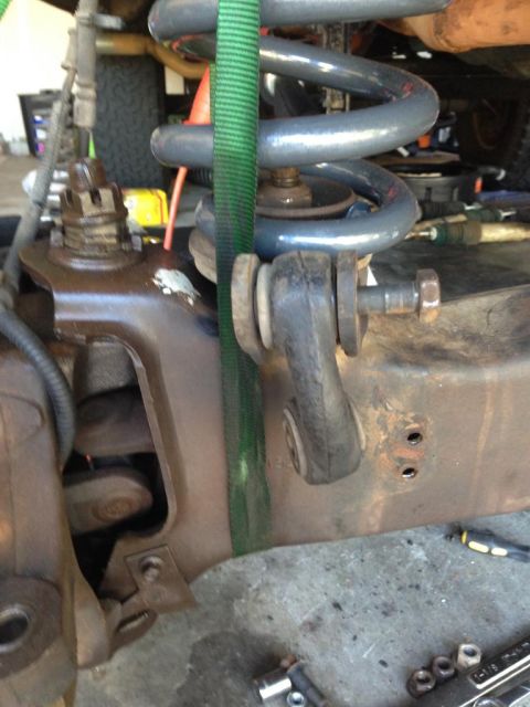 1994 Ford Bronco - Suspension component being held by a green strap during work.