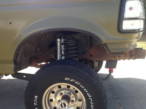 1994 Ford Bronco - Close-up of the front wheel and fender of a modified 1992 Ford Bronco, showing its suspension system.