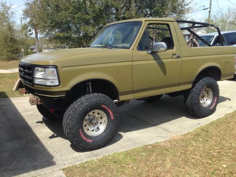 1994 Ford Bronco - Olive green 1994 Ford Bronco modified with a roll cage and off-road tires.