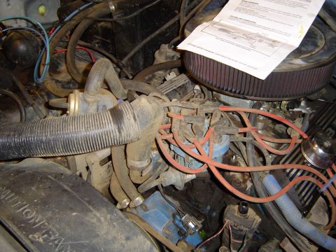 1989 Ford Bronco - Close-up view of a vehicle's engine bay, showing various components and a document.