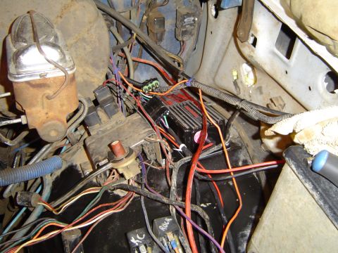 1989 Ford Bronco - Close-up of a vehicle's engine bay wiring, showing a brake fluid reservoir and an ignition module.