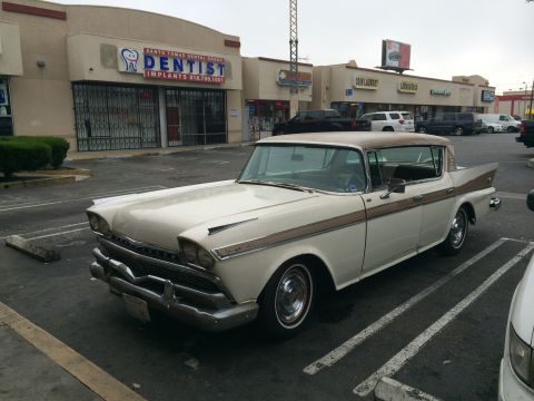 1968 Ford Mustang - A vintage 1958 Studebaker President sedan is parked in a commercial lot.