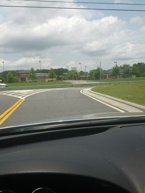 1979 Ford F-150 - View from inside a vehicle looking at a road intersection with buildings and trees in the distance under a cloudy sky.