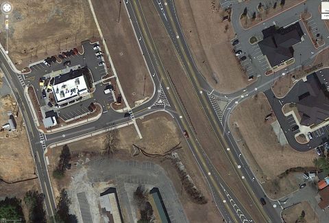 1979 Ford F-150 - Aerial view of a red sedan on a highway, with a McDonald's restaurant and parking lot nearby.