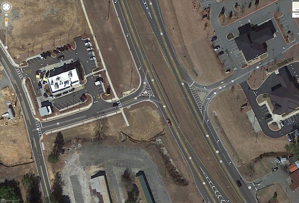 Red sedan driving on a highway next to a McDonald's
