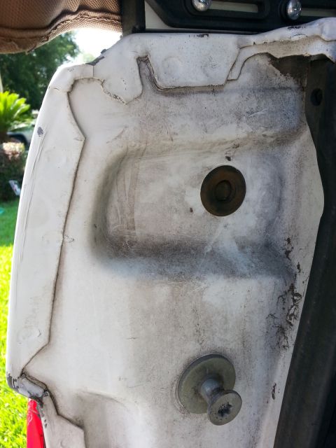 1992 Ford Bronco - The interior wheel well of a white vehicle shows signs of wear and damage, with a prominent bolt visible.