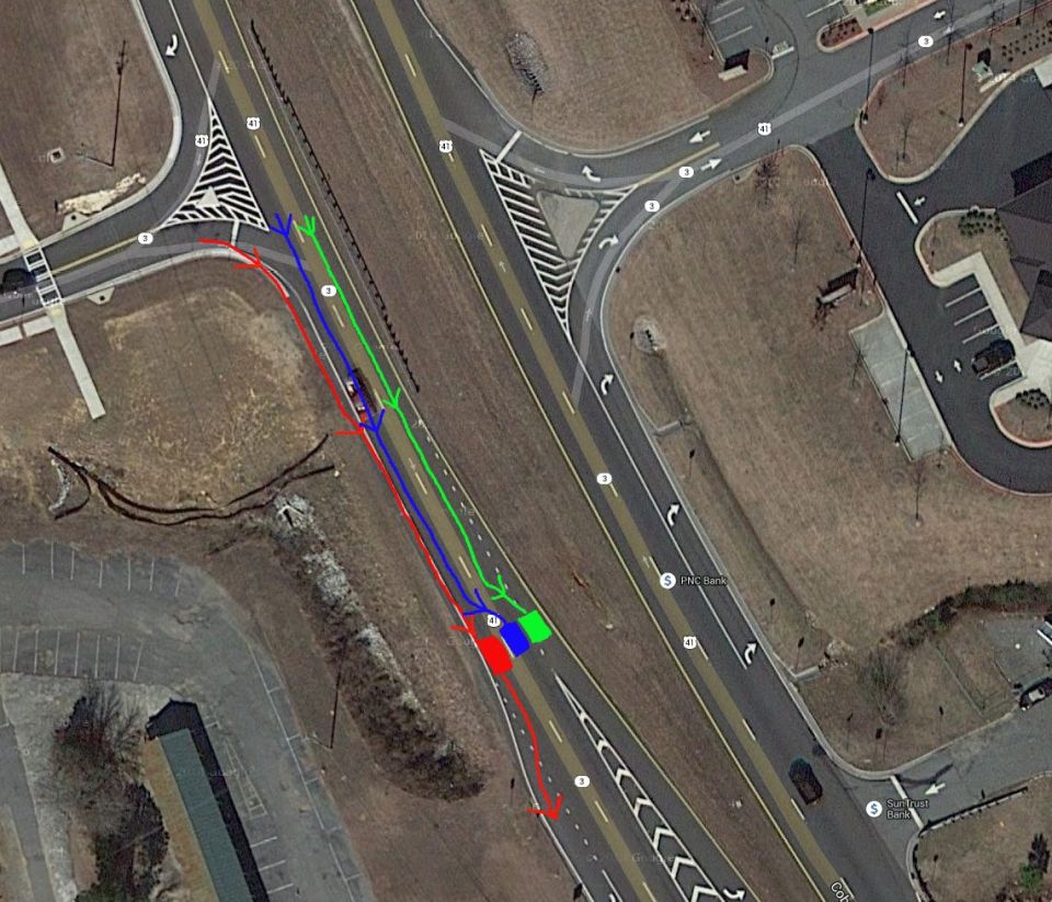 Aerial view of a road intersection with colored arrows indicating traffic flow, and several parked cars