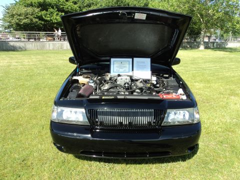 2004 Mercury Grand Marquis - The engine bay of a black 2004 Mercury Grand Marquis is displayed with the hood open, two documents on display.