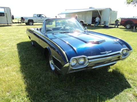2004 Mercury Grand Marquis - A classic blue convertible sits on a grassy field next to a trailer and other vehicles.