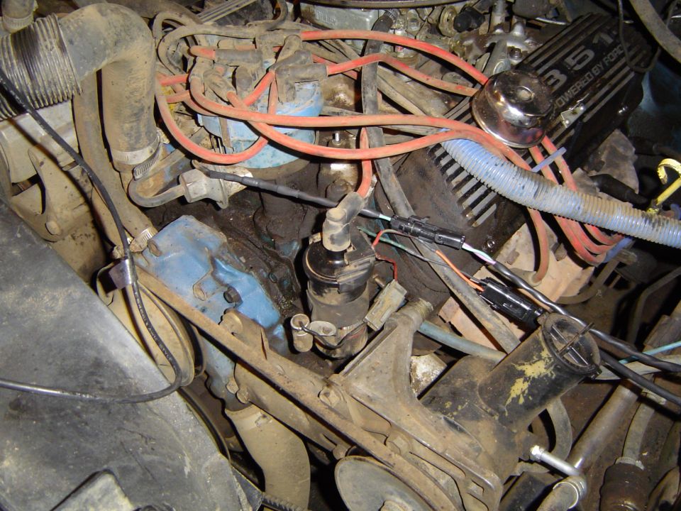 Engine bay of a 1989 Ford Bronco, showing a 351 engine with red spark plug wires and blue distributor cap