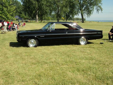 2004 Mercury Grand Marquis - A black 1965 Plymouth Belvedere coupe is parked on a grassy field with trees in the background.