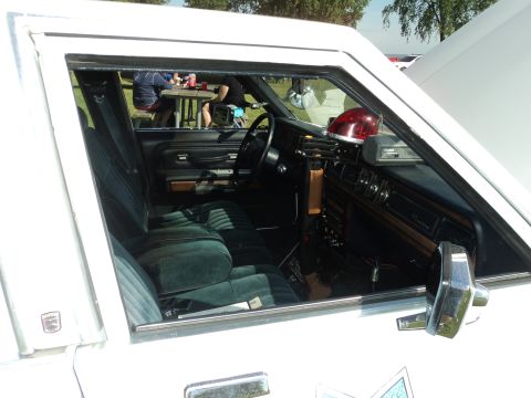 2004 Mercury Grand Marquis - The interior of a white car shows green velour seats and a red light bar on the dashboard.