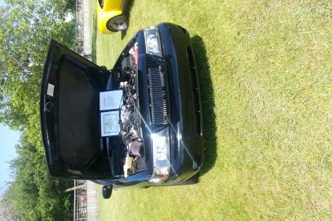 2004 Mercury Grand Marquis - A black sedan with its hood open displays its engine and two documents on a grassy field, with another yellow vehicle visible in the backgr…