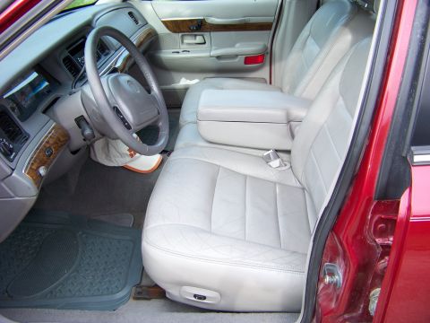1999 Mercury Grand Marquis - Interior view of a red car with light gray leather seats and wood trim accents.