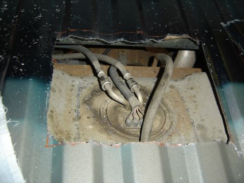 1996 Ford Bronco - Access hole cut into the vehicle's floor reveals the fuel pump assembly and associated hoses.