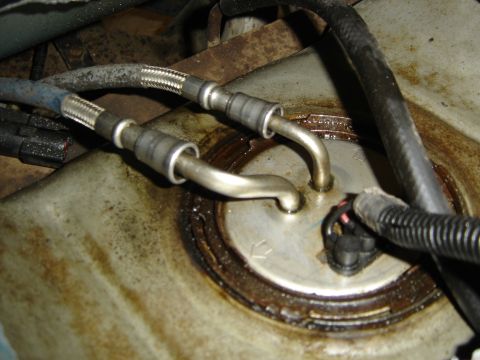 1996 Ford Bronco - Close-up view of a vehicle's fuel pump assembly, showing braided fuel lines and an electrical connector.