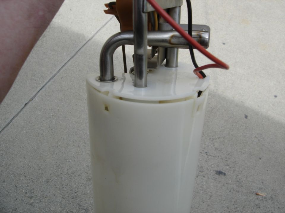 Fuel pump assembly with metal lines and electrical wires against a concrete surface