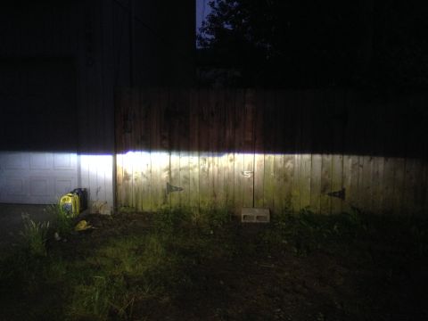 1992 Ford F-150 - Headlights cast a bright beam across a weathered wooden fence in the darkness.