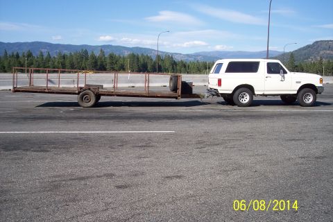 1990 Ford Bronco - 1990 Ford Bronco tows a flatbed trailer on a sunny day with mountains in the background.