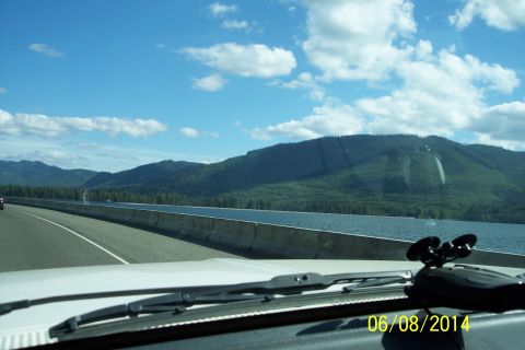 1990 Ford Bronco - A scenic drive unfolds with a highway, water, and mountains visible from the car's dashboard.