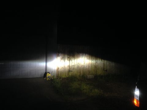 1992 Ford F-150 - Headlights illuminate a fence and garage door, with a portion of a vehicle visible on the right.