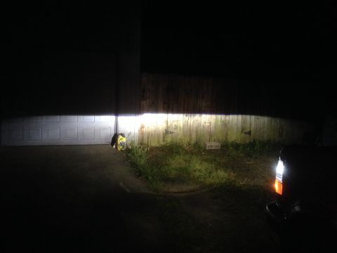 1992 Ford F-150 - Headlights are on, casting a bright beam across a garage door and fence.