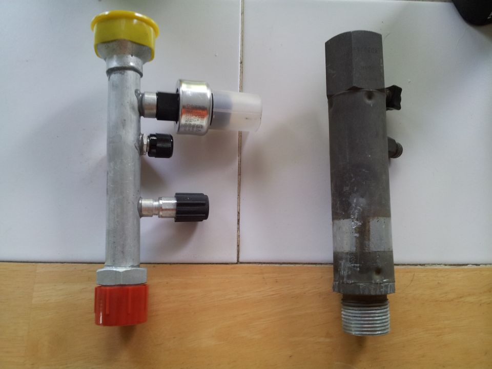 Two automotive AC service valves, one with a yellow cap and red base, the other dark and hexagonal at the top