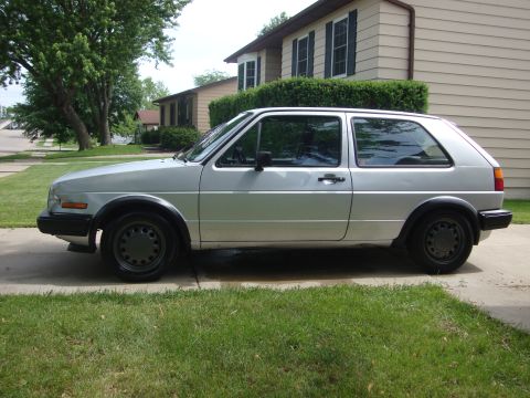 1985 Volkswagen GTI - A silver 1985 Volkswagen GTI is parked on a driveway in front of a house.
