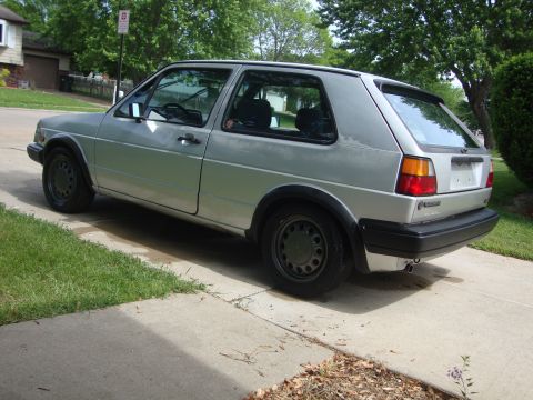 1985 Volkswagen GTI - A silver 1985 Volkswagen Golf is parked on a concrete driveway in front of a house.