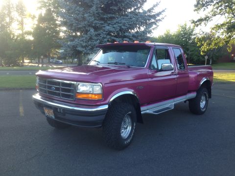 1992 Ford F-150 - This purple 1992 Ford F-150 truck is shown from a three-quarter front angle under trees.