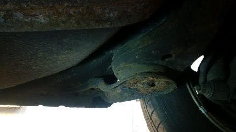 1994 Ford Thunderbird - Close-up view of rusted underbody components and a tire, indicating the need for rust repair.