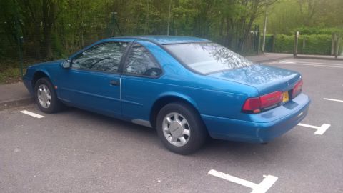 1994 Ford Thunderbird - This blue 1994 Ford Thunderbird is parked in a lot, showing its rear profile.