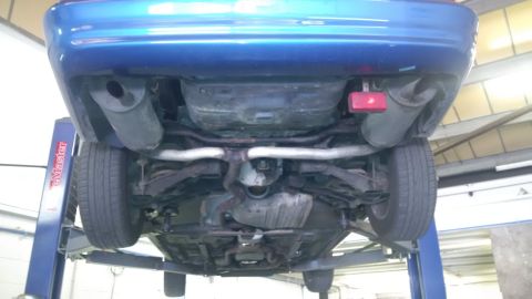 1994 Ford Thunderbird - The undercarriage of a blue vehicle is visible as it's raised on a mechanic's lift.